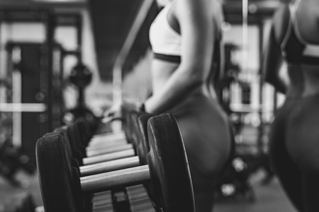 Fitness woman lifting weight in the gym stands next to dumbbellsの写真素材