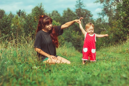 beautiful young mother daughter relaxing sitting grass background summer meadow green grass treesの写真素材