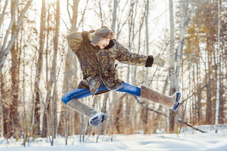 the guy in the hat and boots jumping in the winter in the woodsの写真素材