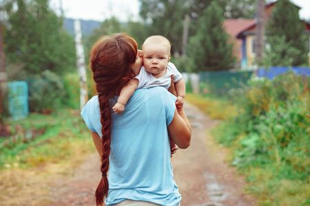 Beautiful mother and her little daughter are outdoors cuddling sitting on the grassの写真素材