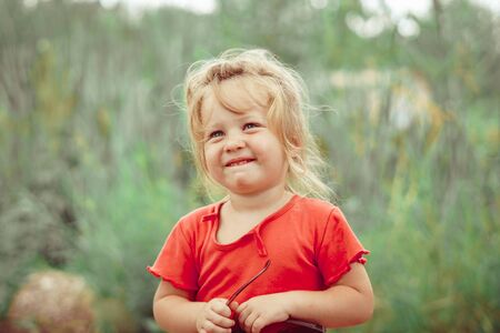 portrait of a happy little girl outdoors in a red shirtの写真素材