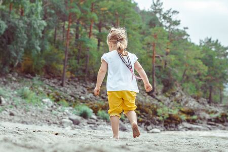 Happy child playing with sand at the beach in summerの写真素材