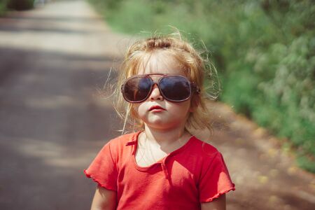 little girl in sunglasses smiling outdoorsの写真素材