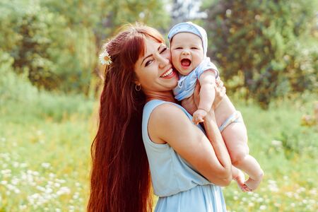 A young mother raised her baby in her armsの写真素材