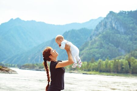 my mother raises a son in his arms laughing upwardsの写真素材