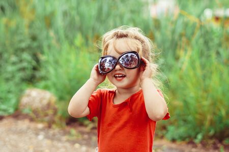 little girl in sunglasses smiling outdoorsの写真素材