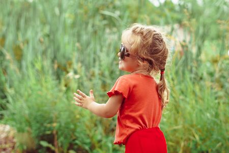 little girl in sunglasses smiling outdoorsの写真素材