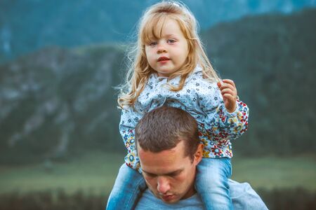 father and daughter on the background of mountains sit and look at nature