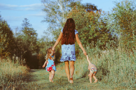 mother walks with children on a forest pathの写真素材