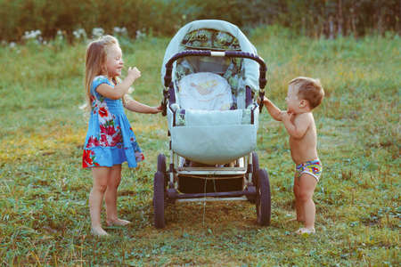 sister plays with her brother in a strollerの写真素材