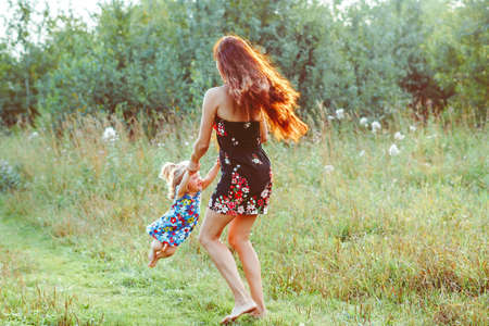 mom whirls with her daughter among the trees