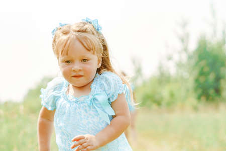 a child runs on the grass, a little girl plays in the meadowの写真素材
