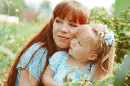 mom hugs her daughter in natureの写真素材