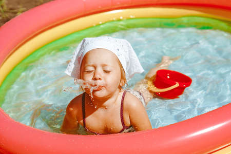 little girl swims in an inflatable poolの写真素材