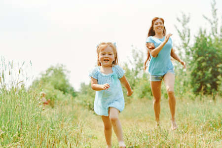 daughter runs towards her mother on the grassの写真素材
