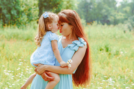 mom hugs her daughter in natureの写真素材