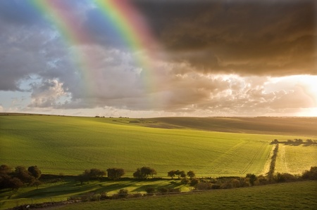 Beautiful double rainbow over stormy dramatic sky over English agricultural countryside landscapeの写真素材