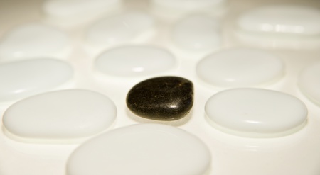 Concept image of isolation or odd one out on single black pebble amongst lots of white pebblesの写真素材