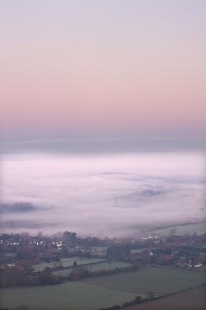 Beautiful colorful sunrise over English landscape with misty blanket over fieldsの写真素材