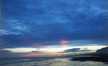 Beautiful vibrant colorful sunset over rocky beach with cliffsの写真素材
