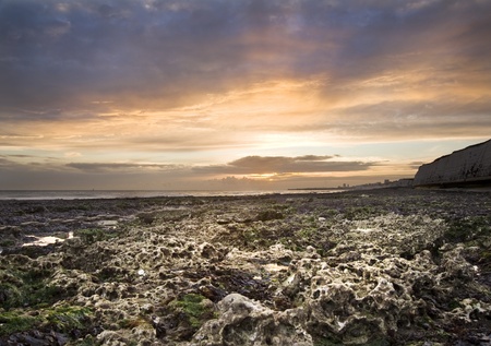 Beautiful sunset over rocky beach with cliffs in backgroundの写真素材