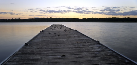 Beautiful jetty extends into lake during colorful sunset in Summerの写真素材