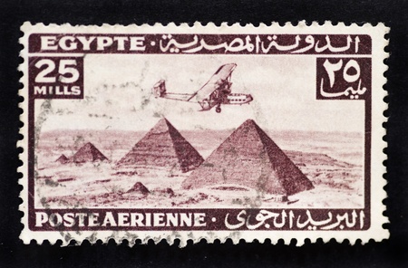 Antique postage stamp showing vintage bi-plane flying over the pyramids in Egypt to represent airmail postageの写真素材
