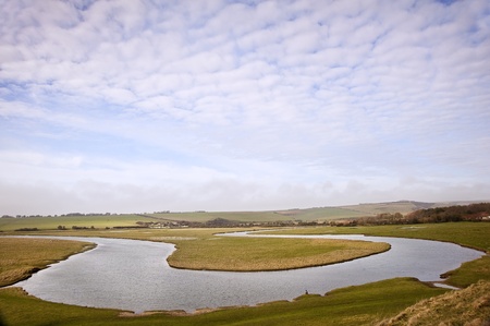 Meandering river twists through beautiful countryside landscape with cloudy blue sky overheadの写真素材