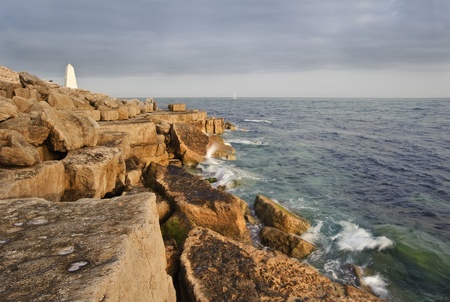 Waves crashing over rock formation cliffs at sunset with beautiful light on rock facesの写真素材