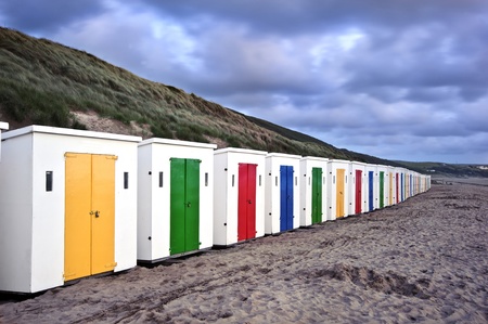 Colorful beach huts on empty beach at stormy sunsetの写真素材