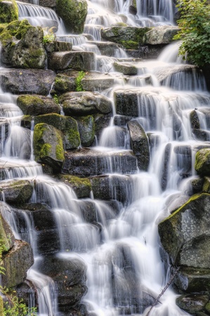 Waterfall cascades flowing over flat rocks in forest landscapeの写真素材