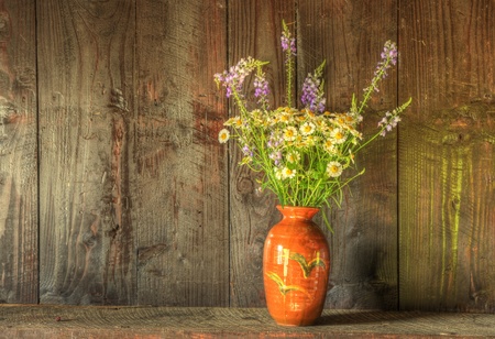 Still life image of dried flowers in rustic vase against weathered wooden backgroundの写真素材