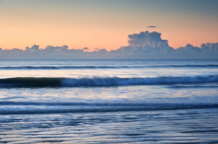 Beautiful low point of view along beach at low tide out to sea with vibrant sunrise skyの写真素材