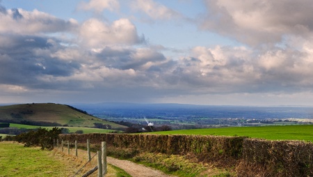 Stunning moody sky with beautiful cloud formations and colors over countryside landscape of path leading into distanceの写真素材