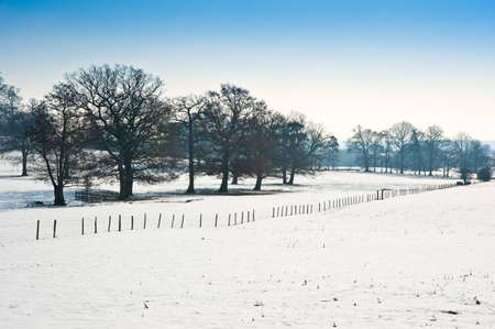 Countryside landscape across rural setting with Winter snow on ground and bright blue sky backgroundの写真素材
