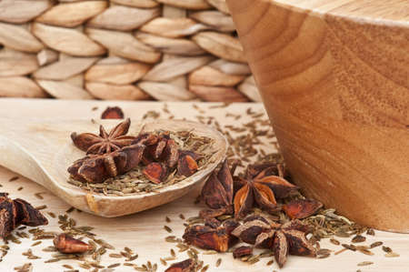 Star anise and cumin seed herbs in kitchen setting with rustic wooden utensils