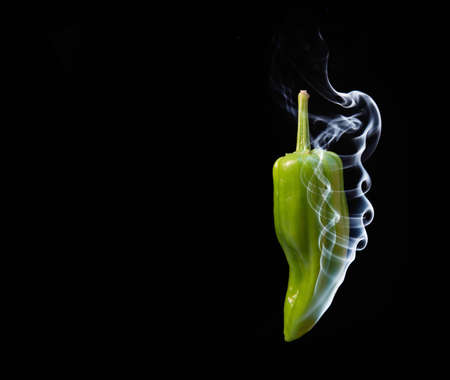 Concept of hot green chilli pepper with smoke coming out of tipの写真素材