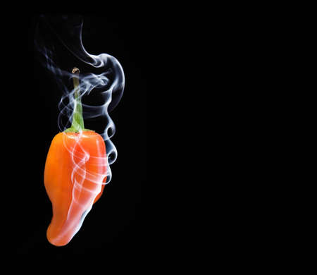 Hot orange chilli pepper with smoke coming out of tip hot conceptの写真素材