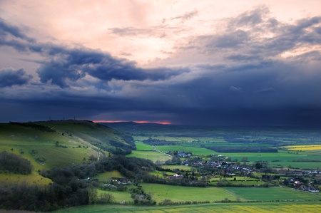 Dark moody skies form over bright fresh Spring countryside landscapeの写真素材