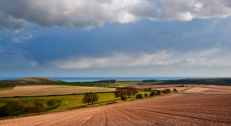 Beautiful landscape over agricultural fields with moody sky and invigorating sunlightの写真素材