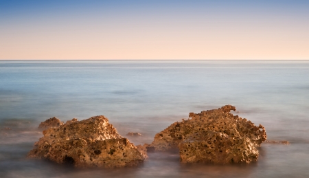 Stunning Summerr sunset over ocean with rocks and vibrant colors