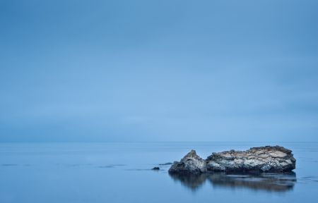 Long exposure moody dramatic seascape with rocks and motion blurの写真素材