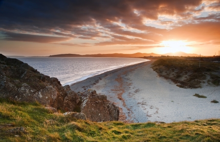 View along West coast of Wales towards beautiful sunset with sunbeams and stunning clouds formationsの写真素材
