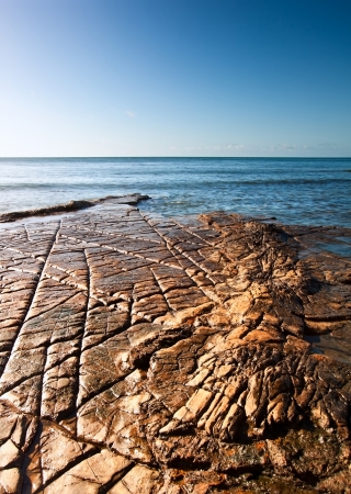 Seascape with Kimmeridgian rock ledges extending out to sea on blue sky dayの写真素材