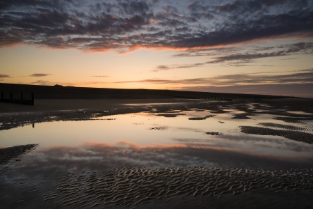 Beautiful sunrise reflected in low tide water pools on beach landscapeの写真素材