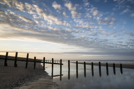 Beautiful sunrise reflected in low tide water pools on beach landscapeの写真素材