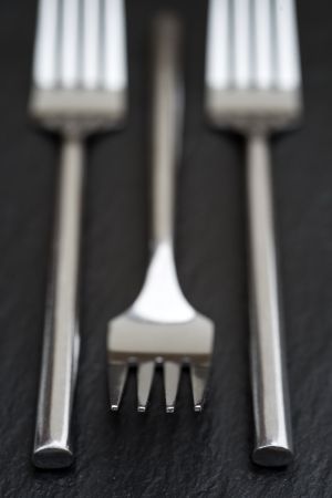 Macro image of modern cutlery forks on rustic slate backgroundの写真素材