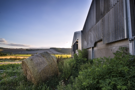 Old barn and hay bales in Summer countryside landscape