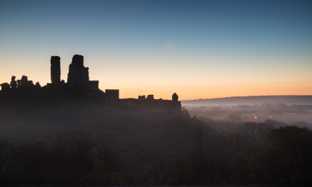 Vibrant sunrise over medieval castle ruins with fog in rural landscapeの写真素材