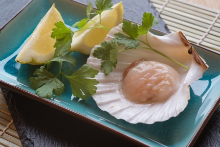 Fresh scallop in shell with lemon and parsley garnish